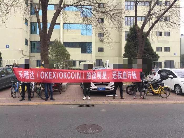 4 名 OKcoin 的投资人来到 OKcoin 的办公地点楼下拉横幅。图片来源于网络